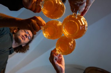 Prag, Çek Cumhuriyeti, 5 Ağustos 2023. Sinematik bakış açısı fotoğrafı. Aşağıdan bir grup kupa kadeh tokuştururken görülüyor. Paylaşılan içkinin yaşam tarzı.