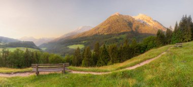 Berchtesgaden Ulusal Parkı, Yukarı Bavyera Alpleri, Almanya, Avrupa 'da gün batımında Hintersee Gölü yakınlarında yol ve bank ile Meadow. Gökyüzü yolu kırpılıyor