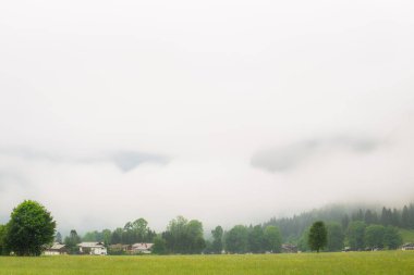 Resimli bir köy, yemyeşil bir alp vadisinde sisli bir dağın eteğinde, sakin bir manzara yaratıyor. Berchtesgaden Ulusal Parkı, Alpler Almanya