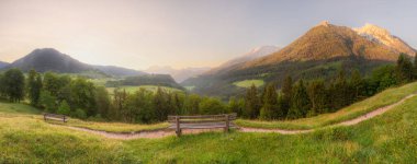 Berchtesgaden Ulusal Parkı, Yukarı Bavyera Alpleri, Almanya, Avrupa 'da gün batımında Hintersee Gölü yakınlarında yol ve bank ile Meadow. Gökyüzü yolu kırpılıyor