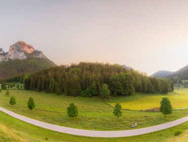 Berchtesgaden Ulusal Parkı, Yukarı Bavyera Alpleri, Almanya, Avrupa 'da gün batımında Hintersee Gölü yakınlarında yol ve bank ile Meadow. Gökyüzü yolu kırpılıyor