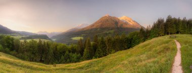 Berchtesgaden Ulusal Parkı, Yukarı Bavyera Alpleri, Almanya, Avrupa 'da gün batımında Hintersee Gölü yakınlarında yol ve bank ile Meadow. Gökyüzü yolu kırpılıyor