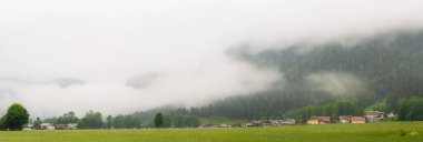 Resimli bir köy, yemyeşil bir alp vadisinde sisli bir dağın eteğinde, sakin bir manzara yaratıyor. Berchtesgaden Ulusal Parkı, Alpler Almanya