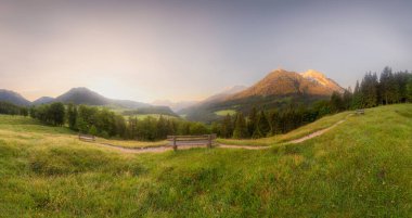 Berchtesgaden Ulusal Parkı, Yukarı Bavyera Alpleri, Almanya, Avrupa 'da gün batımında Hintersee Gölü yakınlarında yol ve bank ile Meadow. Gökyüzü yolu kırpılıyor
