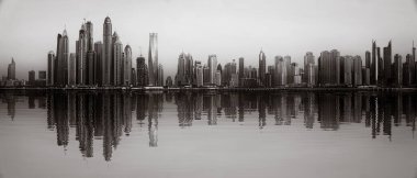 Tek renkli şehir gökdelenleri bulutlu bir gökyüzü altında sakin suyu yansıtan gökdelenler, kentsel gelişim konsepti, Dubai Marina Körfezi BAE