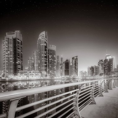 Gökdelenler ve su üzerindeki köprü, siyah-beyaz tarzı, şehir arkaplanı, şehir gelişimi konsepti, Dubai Marina körfezi BAE