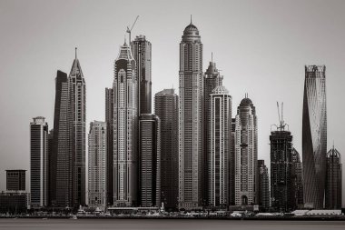 Tek renkli şehir gökdelenleri bulutlu bir gökyüzü altında sakin suyu yansıtan gökdelenler, kentsel gelişim konsepti, Dubai Marina Körfezi BAE