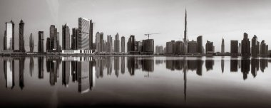 Tek renkli şehir gökdelenleri bulutlu bir gökyüzü altında sakin suyu yansıtan gökdelenler, kentsel gelişim konsepti, Dubai Marina Körfezi BAE