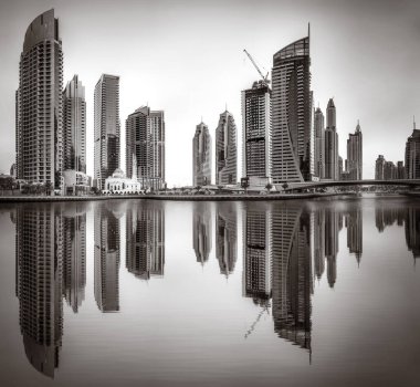 Tek renkli şehir gökdelenleri bulutlu bir gökyüzü altında sakin suyu yansıtan gökdelenler, kentsel gelişim konsepti, Dubai Marina Körfezi BAE