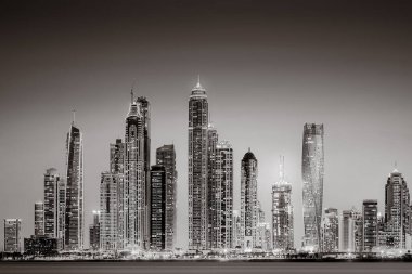 Aydınlatılmış gökdelenleri ve gece siyah beyaz rıhtımlı şehir silüeti, kentsel gelişim konsepti, Dubai Marina Körfezi BAE