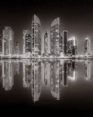 Aydınlatılmış gökdelenleri ve gece siyah beyaz rıhtımlı şehir silüeti, kentsel gelişim konsepti, Dubai Marina Körfezi BAE