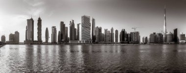 Tek renkli şehir gökdelenleri bulutlu bir gökyüzü altında sakin suyu yansıtan gökdelenler, kentsel gelişim konsepti, Dubai Marina Körfezi BAE