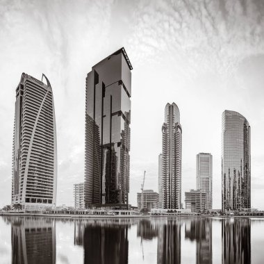 Tek renkli şehir gökdelenleri bulutlu bir gökyüzü altında sakin suyu yansıtan gökdelenler, kentsel gelişim konsepti, Dubai Marina Körfezi BAE