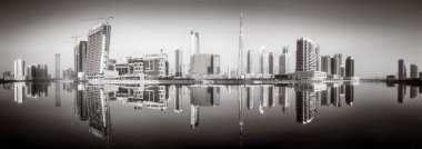 Tek renkli şehir gökdelenleri bulutlu bir gökyüzü altında sakin suyu yansıtan gökdelenler, kentsel gelişim konsepti, Dubai Marina Körfezi BAE