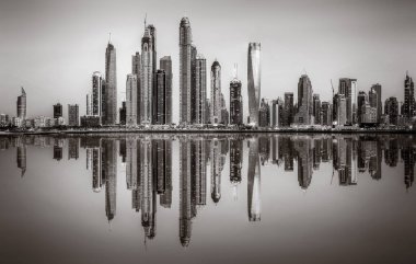 Tek renkli şehir gökdelenleri bulutlu bir gökyüzü altında sakin suyu yansıtan gökdelenler, kentsel gelişim konsepti, Dubai Marina Körfezi BAE