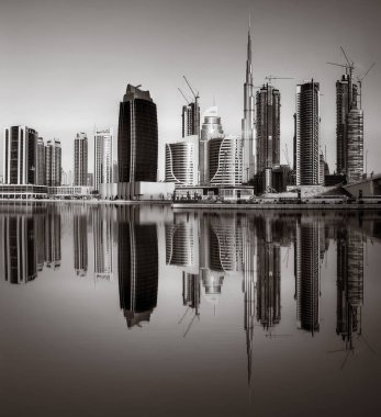 Tek renkli şehir gökdelenleri bulutlu bir gökyüzü altında sakin suyu yansıtan gökdelenler, kentsel gelişim konsepti, Dubai Marina Körfezi BAE