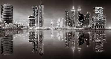 Aydınlatılmış gökdelenleri ve gece siyah beyaz rıhtımlı şehir silüeti, kentsel gelişim konsepti, Dubai Marina Körfezi BAE