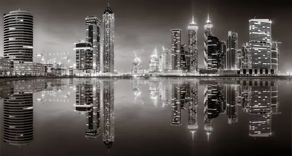 Aydınlatılmış gökdelenleri ve gece siyah beyaz rıhtımlı şehir silüeti, kentsel gelişim konsepti, Dubai Marina Körfezi BAE