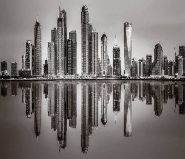 Tek renkli şehir gökdelenleri bulutlu bir gökyüzü altında sakin suyu yansıtan gökdelenler, kentsel gelişim konsepti, Dubai Marina Körfezi BAE