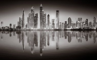 Aydınlatılmış gökdelenleri ve gece siyah beyaz rıhtımlı şehir silüeti, kentsel gelişim konsepti, Dubai Marina Körfezi BAE