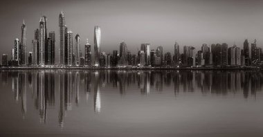 Tek renkli şehir gökdelenleri bulutlu bir gökyüzü altında sakin suyu yansıtan gökdelenler, kentsel gelişim konsepti, Dubai Marina Körfezi BAE