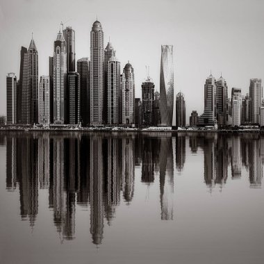 Tek renkli şehir gökdelenleri bulutlu bir gökyüzü altında sakin suyu yansıtan gökdelenler, kentsel gelişim konsepti, Dubai Marina Körfezi BAE