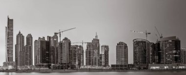 Tek renkli şehir gökdelenleri bulutlu bir gökyüzü altında sakin suyu yansıtan gökdelenler, kentsel gelişim konsepti, Dubai Marina Körfezi BAE