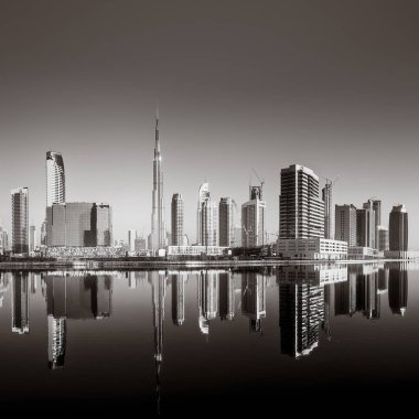 Tek renkli şehir gökdelenleri bulutlu bir gökyüzü altında sakin suyu yansıtan gökdelenler, kentsel gelişim konsepti, Dubai Marina Körfezi BAE