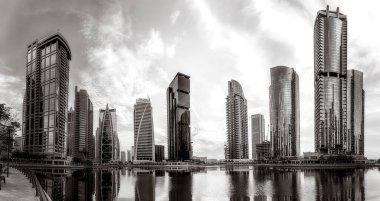 Tek renkli şehir gökdelenleri bulutlu bir gökyüzü altında sakin suyu yansıtan gökdelenler, kentsel gelişim konsepti, Dubai Marina Körfezi BAE