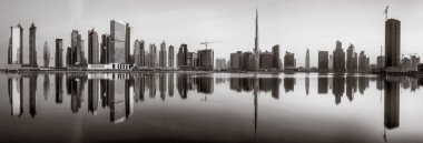 Tek renkli şehir gökdelenleri bulutlu bir gökyüzü altında sakin suyu yansıtan gökdelenler, kentsel gelişim konsepti, Dubai Marina Körfezi BAE