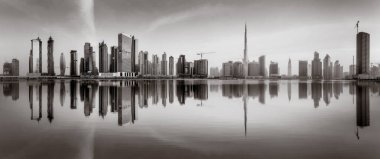 Tek renkli şehir gökdelenleri bulutlu bir gökyüzü altında sakin suyu yansıtan gökdelenler, kentsel gelişim konsepti, Dubai Marina Körfezi BAE