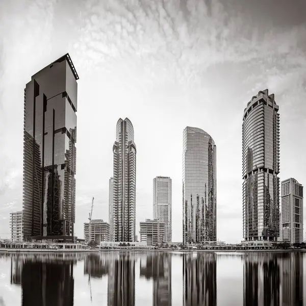 Tek renkli şehir gökdelenleri bulutlu bir gökyüzü altında sakin suyu yansıtan gökdelenler, kentsel gelişim konsepti, Dubai Marina Körfezi BAE