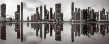 Tek renkli şehir gökdelenleri bulutlu bir gökyüzü altında sakin suyu yansıtan gökdelenler, kentsel gelişim konsepti, Dubai Marina Körfezi BAE