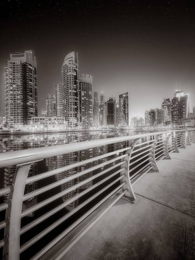 Gökdelenler ve su üzerindeki köprü, siyah-beyaz tarzı, şehir arkaplanı, şehir gelişimi konsepti, Dubai Marina körfezi BAE