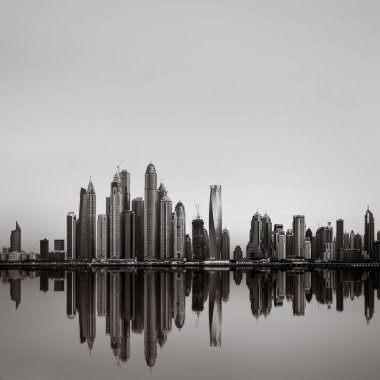 Tek renkli şehir gökdelenleri bulutlu bir gökyüzü altında sakin suyu yansıtan gökdelenler, kentsel gelişim konsepti, Dubai Marina Körfezi BAE