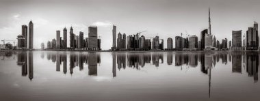 Tek renkli şehir gökdelenleri bulutlu bir gökyüzü altında sakin suyu yansıtan gökdelenler, kentsel gelişim konsepti, Dubai Marina Körfezi BAE