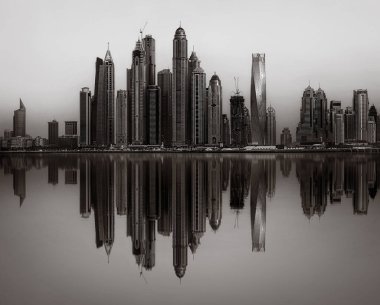 Tek renkli şehir gökdelenleri bulutlu bir gökyüzü altında sakin suyu yansıtan gökdelenler, kentsel gelişim konsepti, Dubai Marina Körfezi BAE