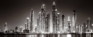 Aydınlatılmış gökdelenleri ve gece siyah beyaz rıhtımlı şehir silüeti, kentsel gelişim konsepti, Dubai Marina Körfezi BAE