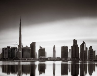 Tek renkli şehir gökdelenleri bulutlu bir gökyüzü altında sakin suyu yansıtan gökdelenler, kentsel gelişim konsepti, Dubai Marina Körfezi BAE