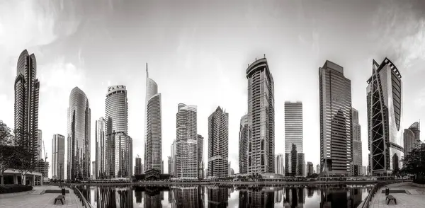 Tek renkli şehir gökdelenleri bulutlu bir gökyüzü altında sakin suyu yansıtan gökdelenler, kentsel gelişim konsepti, Dubai Marina Körfezi BAE