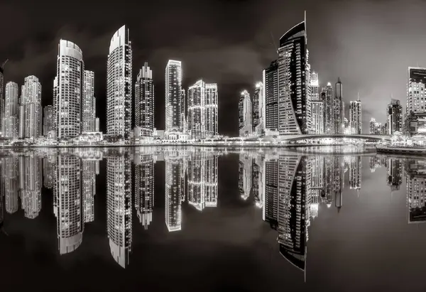 Aydınlatılmış gökdelenleri ve gece siyah beyaz rıhtımlı şehir silüeti, kentsel gelişim konsepti, Dubai Marina Körfezi BAE