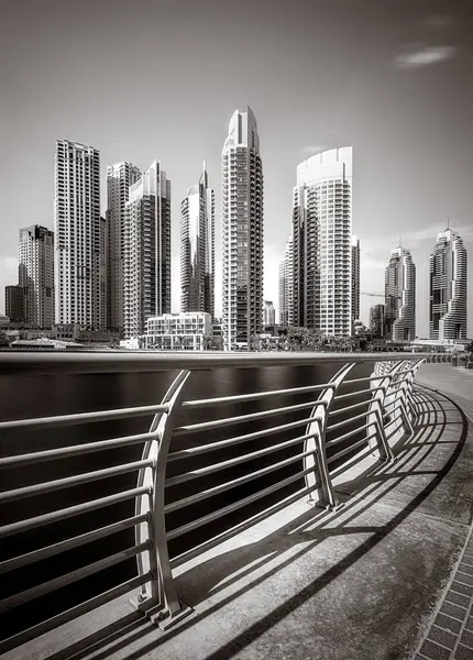 Gökdelenler ve su üzerindeki köprü, siyah-beyaz tarzı, şehir arkaplanı, şehir gelişimi konsepti, Dubai Marina körfezi BAE