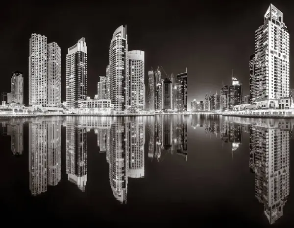 Aydınlatılmış gökdelenleri ve gece siyah beyaz rıhtımlı şehir silüeti, kentsel gelişim konsepti, Dubai Marina Körfezi BAE