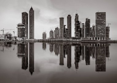 Tek renkli şehir gökdelenleri bulutlu bir gökyüzü altında sakin suyu yansıtan gökdelenler, kentsel gelişim konsepti, Dubai Marina Körfezi BAE