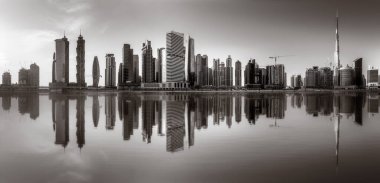 Tek renkli şehir gökdelenleri bulutlu bir gökyüzü altında sakin suyu yansıtan gökdelenler, kentsel gelişim konsepti, Dubai Marina Körfezi BAE