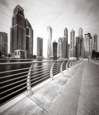Gökdelenler ve su üzerindeki köprü, siyah-beyaz tarzı, şehir arkaplanı, şehir gelişimi konsepti, Dubai Marina körfezi BAE