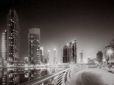 Gökdelenler ve su üzerindeki köprü, siyah-beyaz tarzı, şehir arkaplanı, şehir gelişimi konsepti, Dubai Marina körfezi BAE
