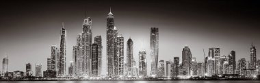 Aydınlatılmış gökdelenleri ve gece siyah beyaz rıhtımlı şehir silüeti, kentsel gelişim konsepti, Dubai Marina Körfezi BAE