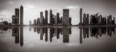 Tek renkli şehir gökdelenleri bulutlu bir gökyüzü altında sakin suyu yansıtan gökdelenler, kentsel gelişim konsepti, Dubai Marina Körfezi BAE