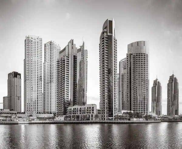 Tek renkli şehir gökdelenleri bulutlu bir gökyüzü altında sakin suyu yansıtan gökdelenler, kentsel gelişim konsepti, Dubai Marina Körfezi BAE